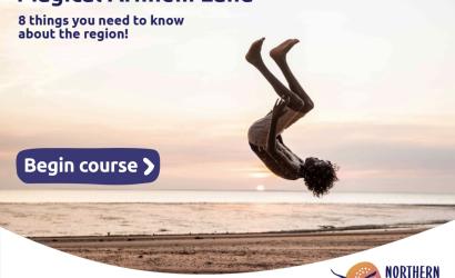 Boy doing a backflip on the beach at sunset